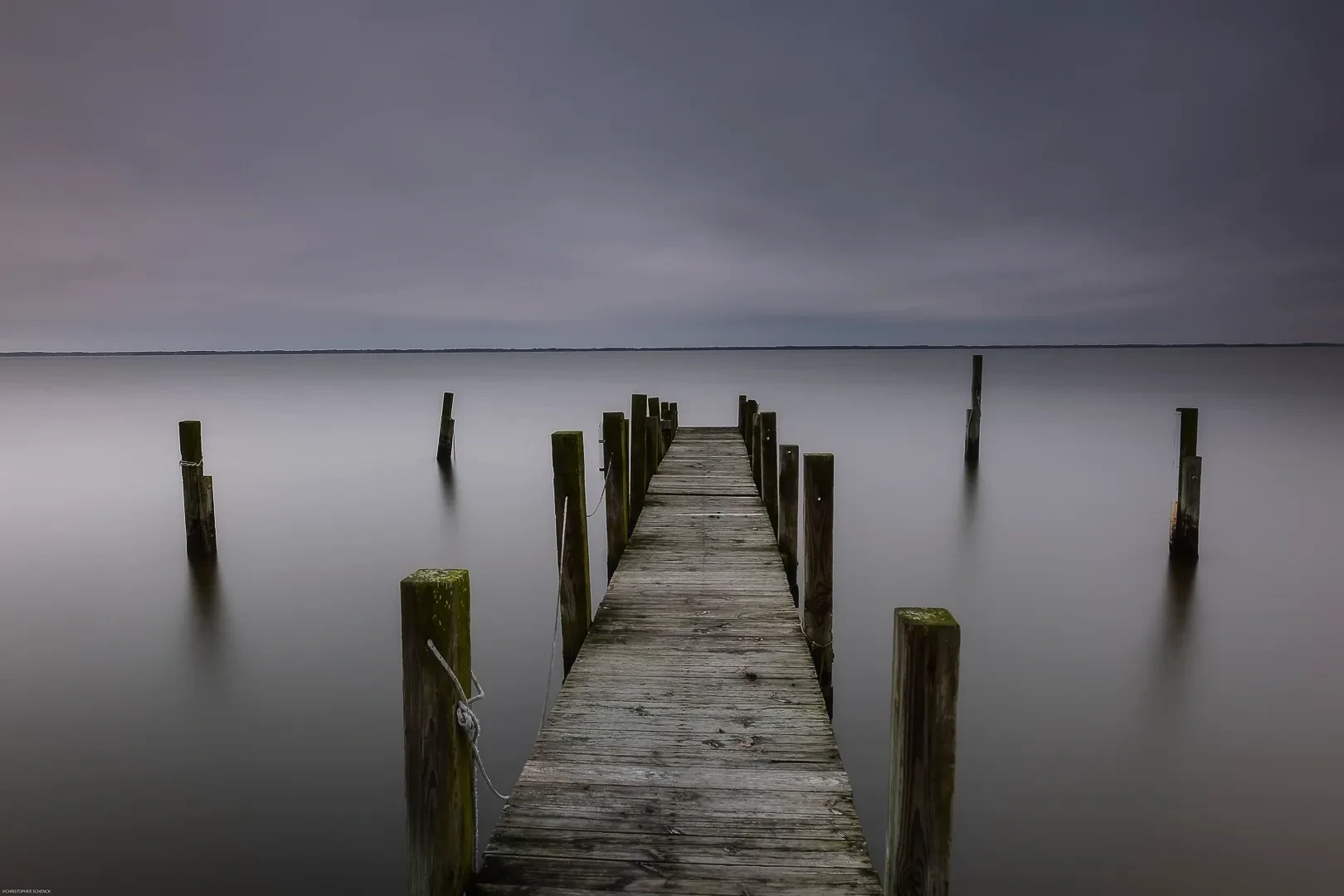 Wooden pier extending into calm water, long exposure