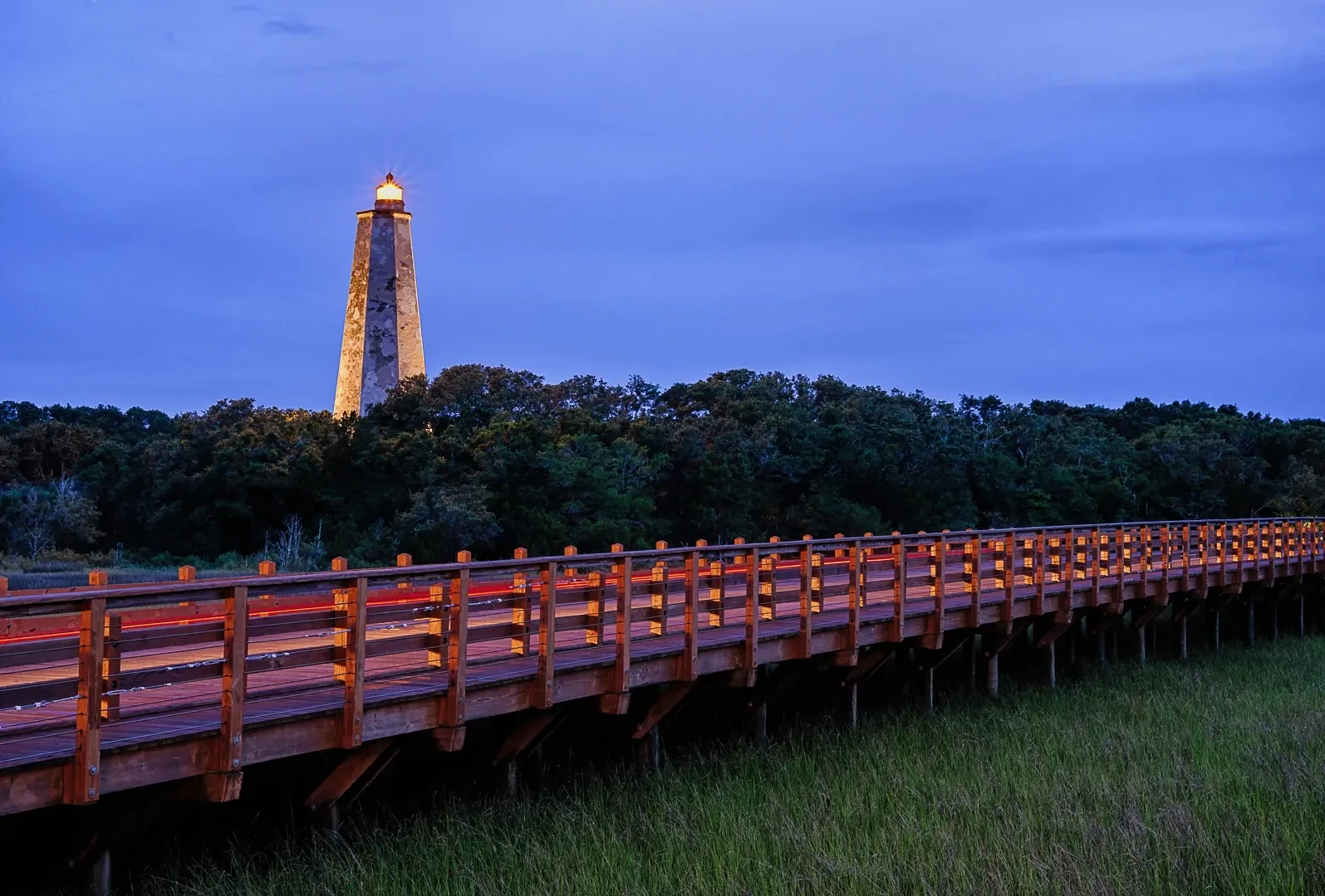 Bald Head Island lighthouse at dusk with illuminated boardwalk