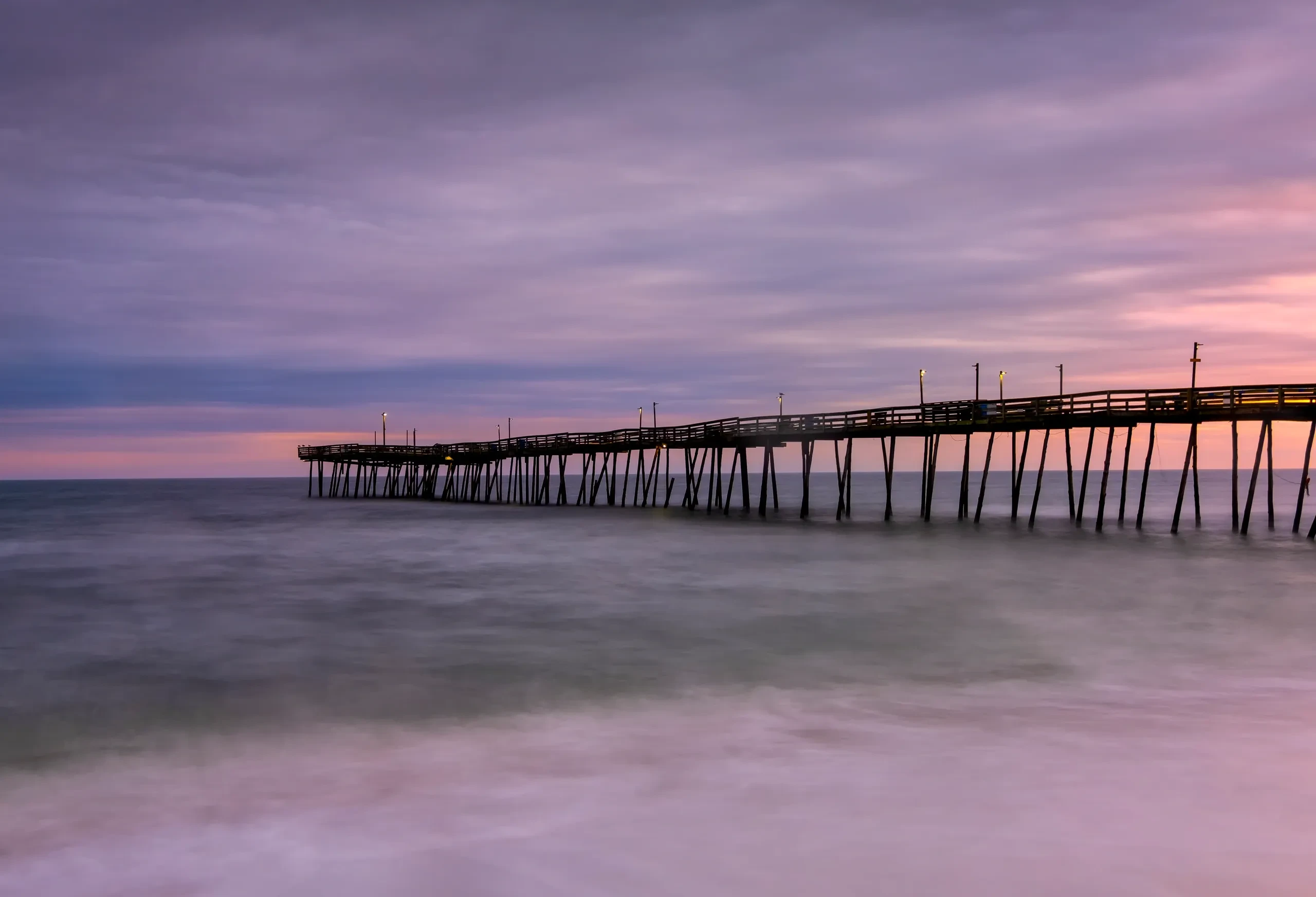 Avalon Pier at sunrise with long-exposure silky surf and purple-pink sky